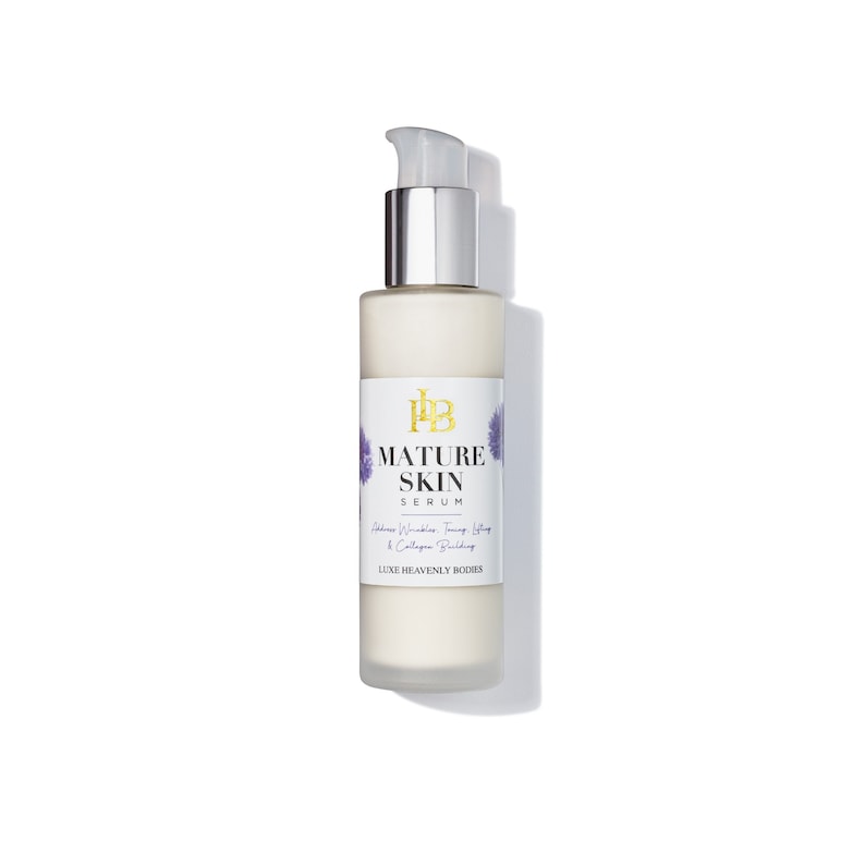 May include: A white bottle of Luxe Heavenly Bodies Mature Skin Serum with a silver pump top. The bottle has a purple and white floral design and the text "Mature Skin Serum" and "Reduces Wrinkles, Firms Skin & Collagen Building".