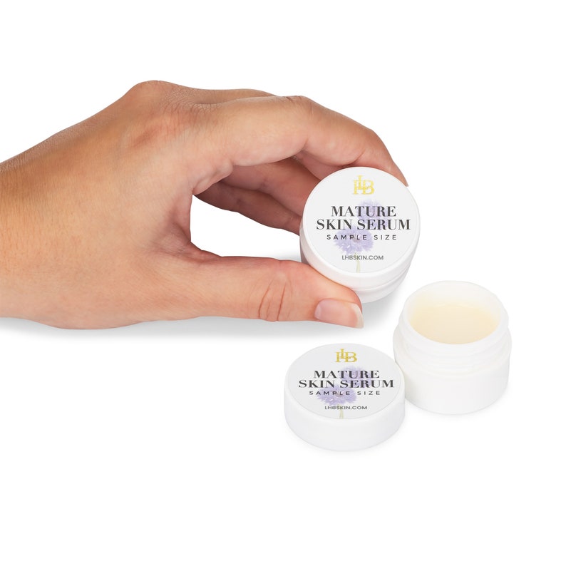 May include: Two small white jars with a purple and gold label that reads "Mature Skin Serum Sample Size" and the website address "LHSKIN.COM".