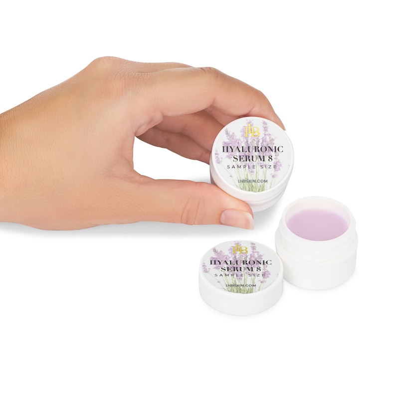May include: Two small white jars with purple lids. The jars are labeled "HYALURONIC SERUM 8 SAMPLE SIZE" with a lavender flower design. The text "LIRSKIN.COM" is printed on the label.