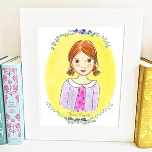 May include: A framed illustration of a girl with red hair and a purple and pink checked shirt. The girl is surrounded by a wreath of green leaves and blue flowers. The text "Fern Arabelle" is written below the girl.