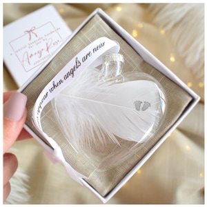 Boule de Noël en verre en forme de cœur et de pieds de bébé, souvenir commémoratif, avec plumes et empreintes de pieds de bébé.