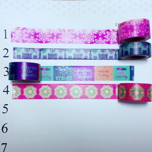 May include: Five rolls of washi tape with different designs. The first roll has a pink and white mandala pattern. The second roll has a purple and white elephant pattern. The third roll has a teal, pink, and purple pattern with the words "Embrace the Journey", "Have Courage", "Strong", "Embrace the Journey", and "Enjoy Today". The fourth roll has a pink and green mandala pattern. The fifth roll has a pink and red mandala pattern.