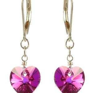 May include: A pair of silver dangle earrings with pink heart-shaped crystal accents.