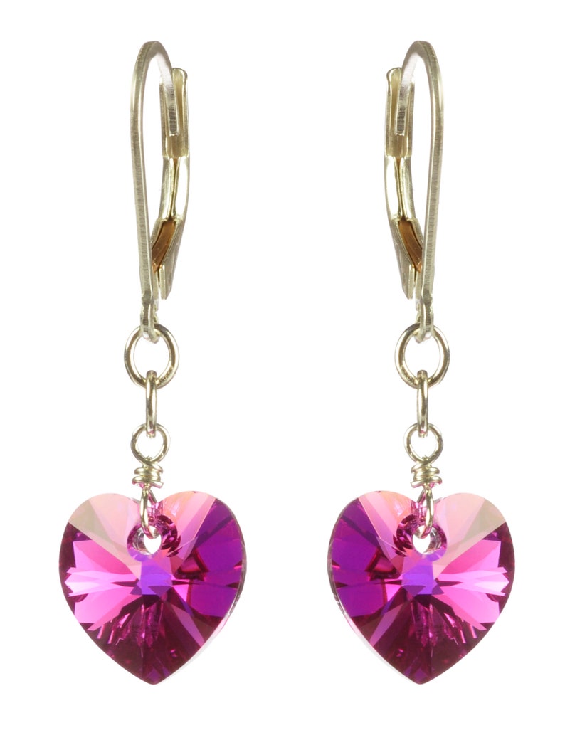May include: A pair of silver dangle earrings with pink heart-shaped crystal accents.