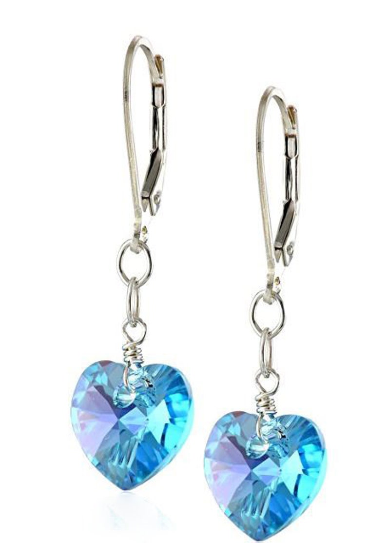 May include: A pair of silver dangle earrings with light blue crystal heart charms.