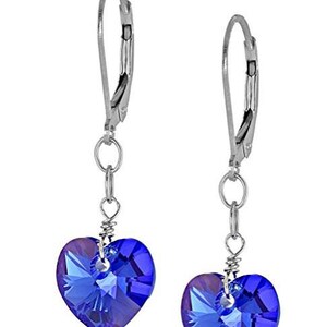 May include: A pair of silver dangle earrings with blue crystal heart charms. The earrings have a leverback closure.