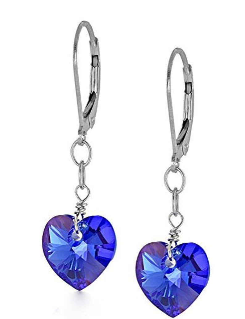 May include: A pair of silver dangle earrings with blue crystal heart charms. The earrings have a leverback closure.