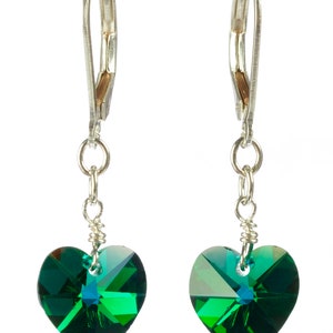 May include: A pair of silver dangle earrings with green heart-shaped crystal accents.