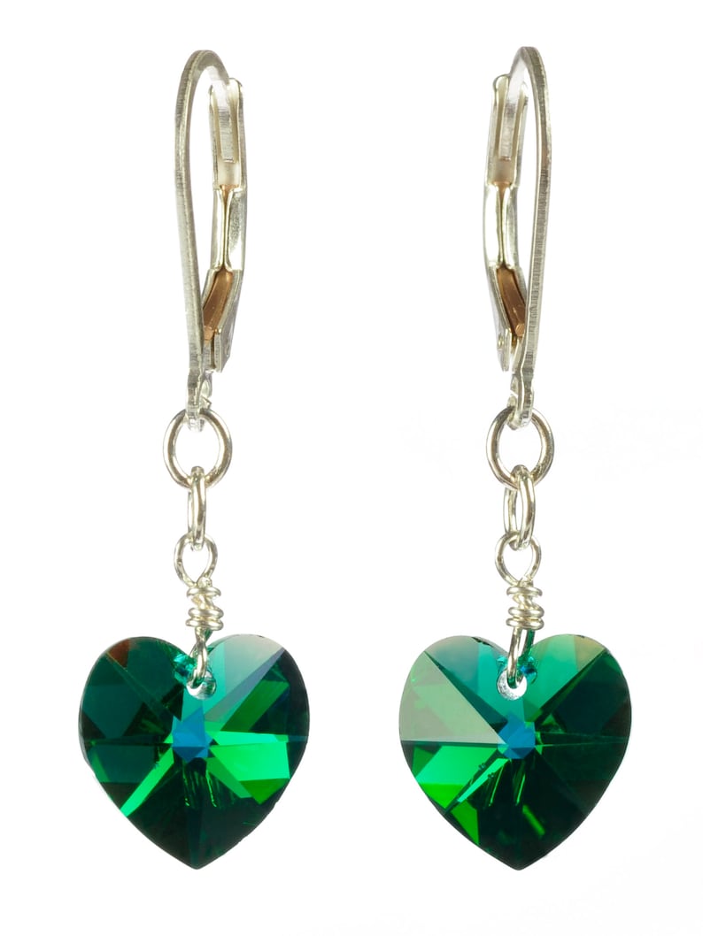 May include: A pair of silver dangle earrings with green heart-shaped crystal accents.