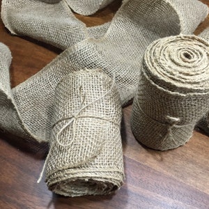 Peut inclure: Deux rouleaux de ruban de toile de jute naturelle, l'un est nou&eacute; avec de la ficelle et l'autre est l&acirc;che. Le ruban est de couleur brun naturel et a une texture rugueuse.