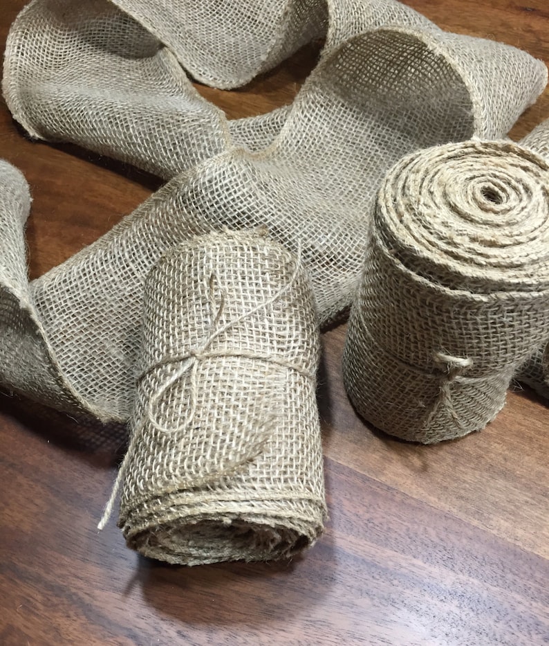 Peut inclure: Deux rouleaux de ruban de toile de jute naturelle, l'un est nou&eacute; avec de la ficelle et l'autre est l&acirc;che. Le ruban est de couleur brun naturel et a une texture rugueuse.