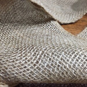 Peut inclure: Un gros plan sur un morceau de tissu de jute naturel avec une texture tiss&eacute;e. Le tissu est brun clair et a une texture rugueuse et rustique.