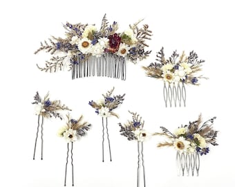 May include: Set of six hair combs decorated with dried flowers. The combs are silver and black, and the flowers are white, purple, and brown.