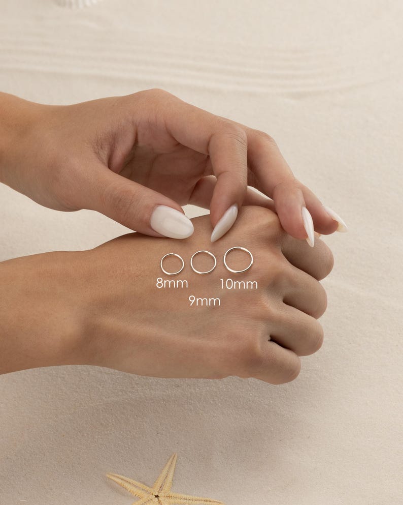 A person's hand is shown wearing three different sizes of rings on the fingers, with the largest ring being 8mm, the medium-sized ring being 10mm, and the smallest ring being 9mm.
