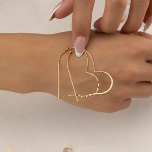 a woman's hand with a gold heart ring