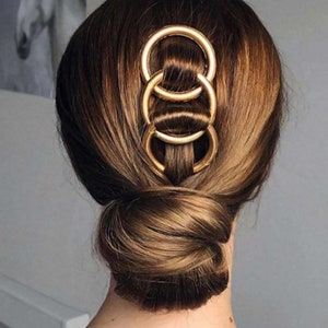 a woman's hair in a bun with two rings in it