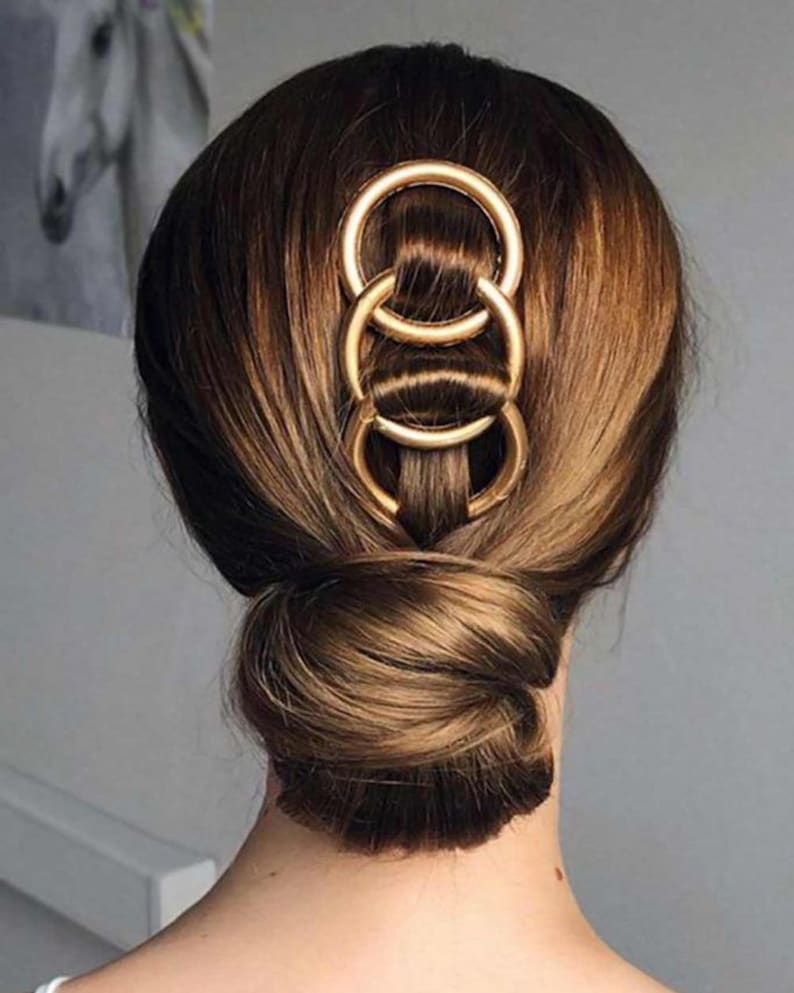 a woman's hair in a bun with two rings in it