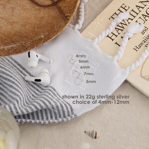 a collection of items, including a straw hat, a book, earbuds, and a piece of paper, all placed on a surface.