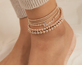 May include: Gold anklet with multiple strands of beads and a delicate "love" charm.