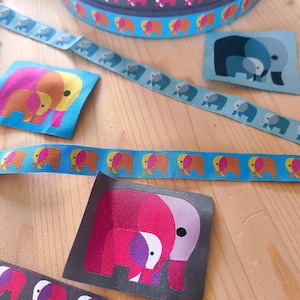 Könnte beinhalten: Eine Sammlung von Stoffbändern und quadratischen Aufnähern mit wiederkehrenden Elefantenmotiven. Die Bänder zeigen Reihen kleiner Elefanten in Orange, Pink und Blau, während die Aufnäher größere, stilisierte Elefantenillustrationen in lebendigen Farbpaletten aus Pink, Lila und Blau aufweisen.