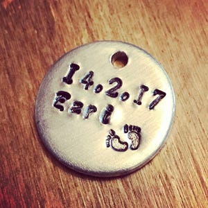 Peut inclure: Un charme rond en argent avec la date "14.2.17" et le mot "Earl" grav&eacute; dessus. Le charme a &eacute;galement une paire de petites empreintes de pas grav&eacute;es dessus.
