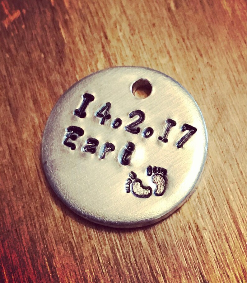 Peut inclure: Un charme rond en argent avec la date "14.2.17" et le mot "Earl" grav&eacute; dessus. Le charme a &eacute;galement une paire de petites empreintes de pas grav&eacute;es dessus.