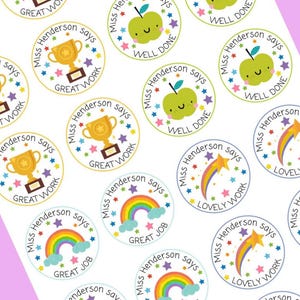 Könnte beinhalten: Eine Sammlung bunter, runder Aufkleber mit verschiedenen Designs und Texten. Die Aufkleber zeigen Bilder einer Trophäe, eines Apfels, eines Regenbogens und eines Sterns, zusammen mit den Sätzen "Great Work", "Well Done", "Great Job" und "Lovely Work".
