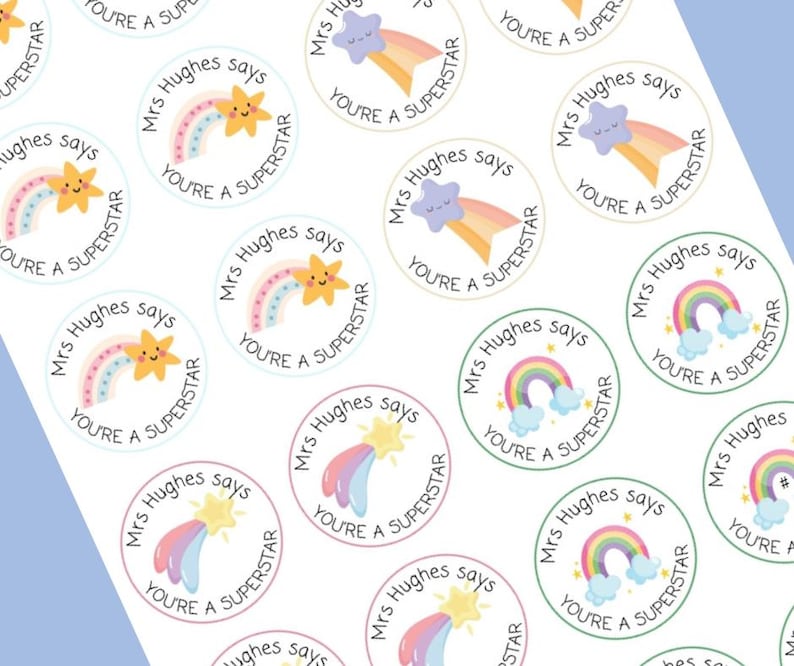 May include: A sheet of round stickers with a white background. Each sticker features a cartoon rainbow, star, or cloud with the text "Mrs Hughes says YOU'RE A SUPERSTAR" in a circular design. The stickers have pastel colors.
