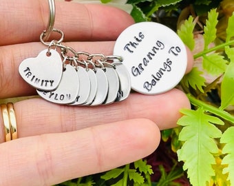 May include: Silver keychain with a round charm that says "This Granny Belongs To" and several heart-shaped charms with names on them, including "Trinity" and "Eylon".