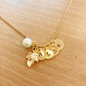 May include: Gold necklace with a pearl charm, a leaf charm, and five small round charms with letters on them. The letters are A, L, I, K, and L.