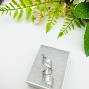 May include: A silver ring with a horseshoe and the word "Handmade" engraved on it. The ring is in a white box.