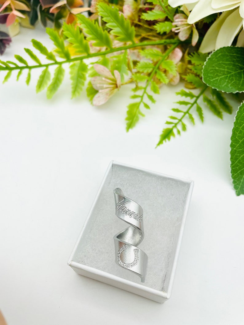 May include: A silver ring with a horseshoe and the word "Handmade" engraved on it. The ring is in a white box.