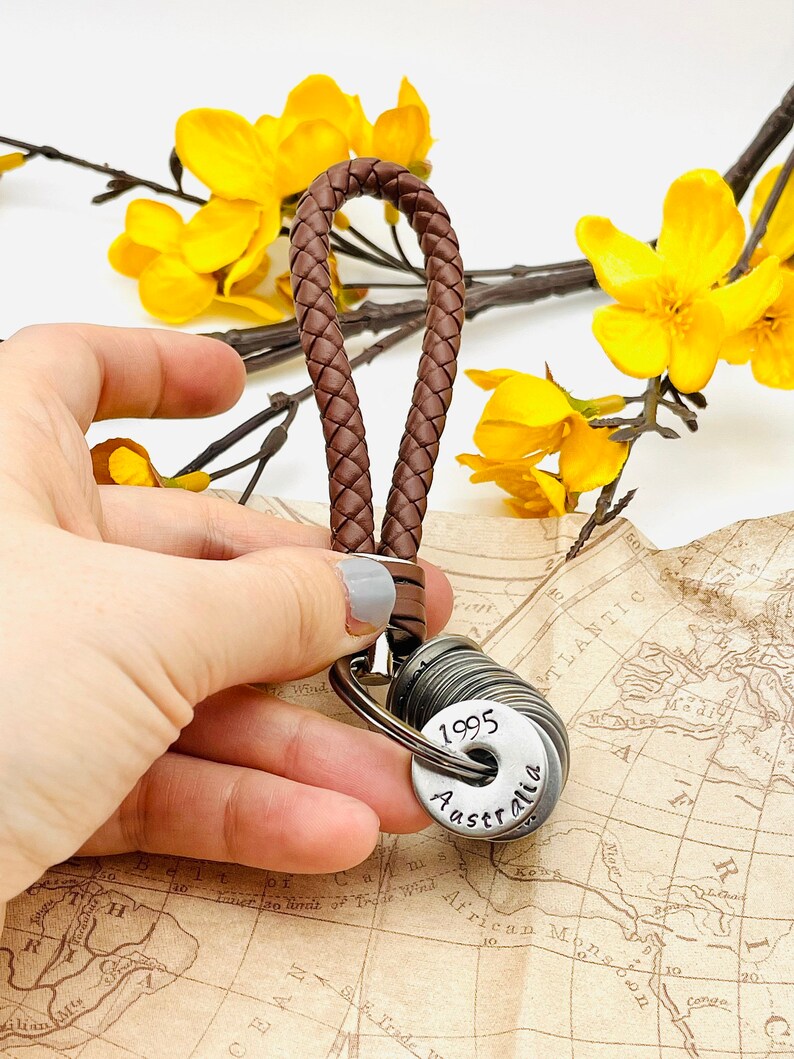 May include: A brown leather keychain with a braided strap and a silver charm with the text "1995 Australia".