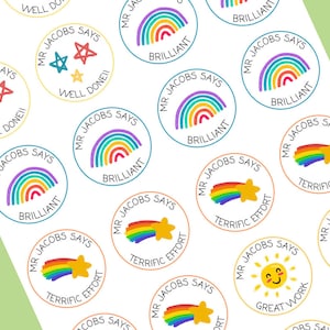 Könnte beinhalten: Ein Satz mit 12 runden, bunten Aufklebern mit Regenbogen-Designs. Jeder Aufkleber zeigt einen anderen Spruch, darunter "Mr. Jacobs Says", "Brilliant", "Terrific Effort" und "Great Work".