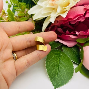 May include: Gold-toned ring with the inscription "Dr." and a medical symbol. The ring is shown on a finger.
