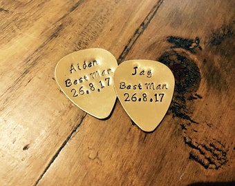 May include: Two gold-colored guitar picks with the text "Aiden Best Man 26.8.17" and "Jay Best Man 26.8.17" engraved on them.