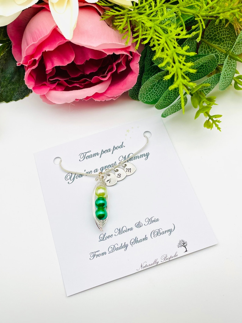 May include: A silver necklace with a pea pod charm and three initial charms. The card reads "Team pea pod. You're a great Mommy. Love Moira & Aria From Daddy Shark (Barry) Naturally Bespoke."