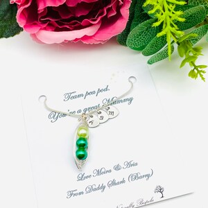 May include: A silver necklace with a pea pod charm and three small heart charms with the letters A, B, and M. The card reads "Team pea pod. You're a great Mummy. Love Moira & Aria From Daddy Shark (Barry) Naturally Bespoke."