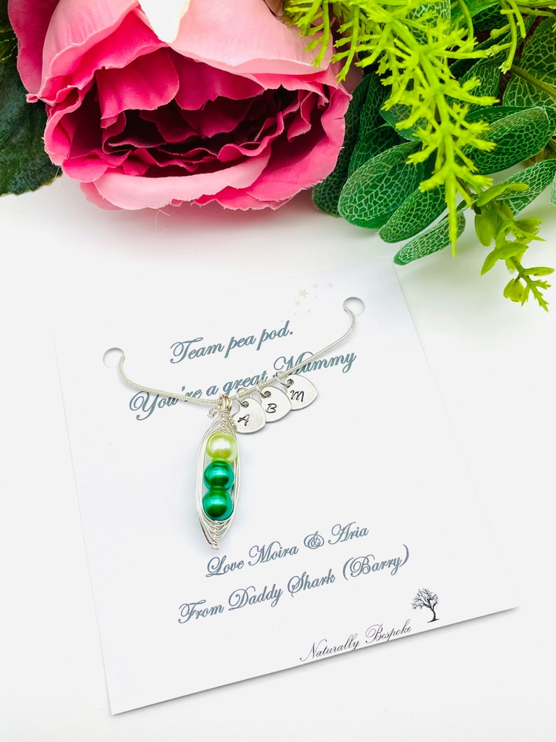 May include: A silver necklace with a pea pod charm and three small heart charms with the letters A, B, and M. The card reads "Team pea pod. You're a great Mummy. Love Moira & Aria From Daddy Shark (Barry) Naturally Bespoke."