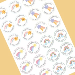 May include: Sheet of round stickers with a rainbow, star, and cloud design. Each sticker has the text "Mrs Hughes says" and "You're a Superstar" in a playful font. The stickers are on a white background.