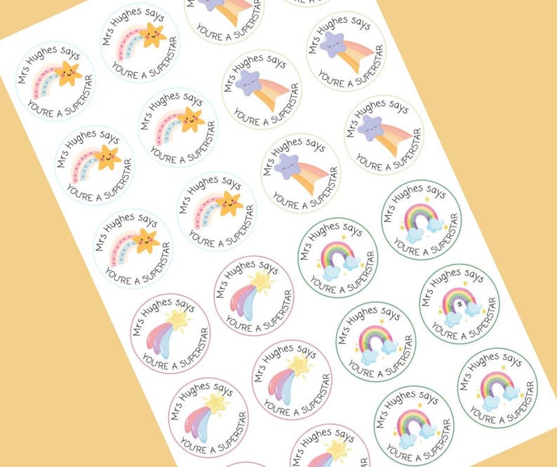 May include: Sheet of round stickers with a rainbow, star, and cloud design. Each sticker has the text "Mrs Hughes says" and "You're a Superstar" in a playful font. The stickers are on a white background.