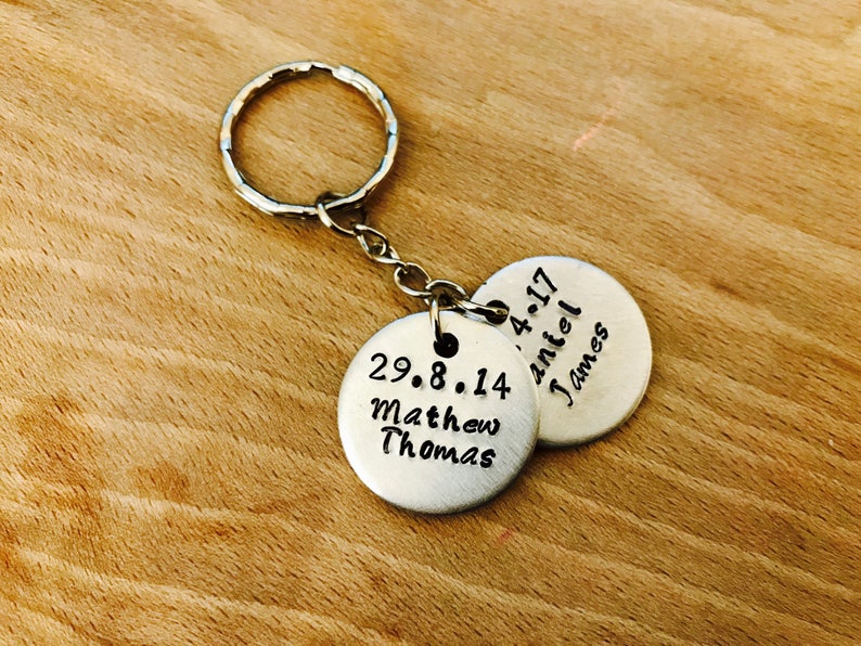 Peut inclure: Porte-cl&eacute;s en argent avec deux &eacute;tiquettes rondes en m&eacute;tal. La premi&egrave;re &eacute;tiquette dit "29.8.14 Matthew Thomas" et la deuxi&egrave;me &eacute;tiquette dit "4.4.17 Daniel James".