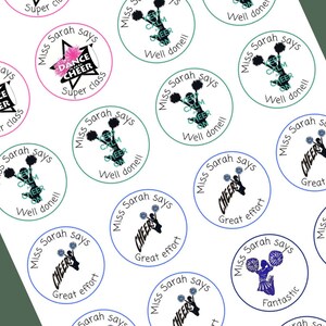 May include: A set of 12 round stickers featuring a cheerleading theme. The stickers are printed with different phrases such as "Miss Sarah says", "Super Class", "Great Effort", "Well Done", "Fantastic", and "Keep Calm and Cheer On". The stickers feature a variety of cheerleading poses and a star with the words "Dance Cheer" on it.