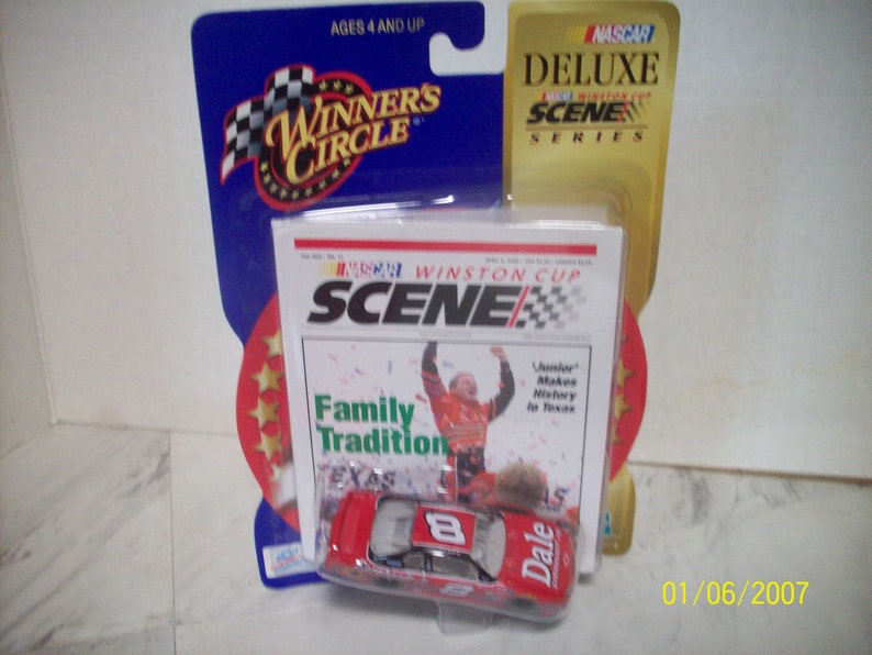 May include: A red and white NASCAR die-cast car with the number 8 and the name Dale on the side. The car is in a plastic package with a magazine cover featuring a photo of Dale Earnhardt Jr. and the text "Winston Cup Scene Family Tradition Texas".