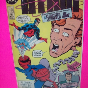 May include: Comic book cover featuring the Power of the Atom, a superhero in a red, blue, and white costume, and the Elongated Man, a superhero with a long, stretched-out body. The cover also features the text "Power of the Atom" and "Guest-starring the one-the-only The Elongated Man."
