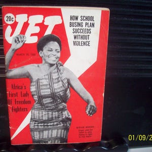 Könnte beinhalten: Ein Vintage-Cover des Jet-Magazins mit einer Frau in einem gemusterten Schal vor rotem Hintergrund. Das Cover enthält den Text „HOW SCHOOL BUSING PLAN SUCCEEDS WITHOUT VIOLENCE“ und „Africa's First Lady Of Freedom Fighters“. Das Magazin ist vom 28. März 1968 datiert.