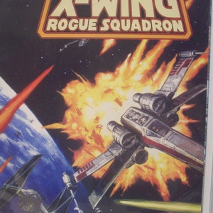 Peut inclure: Une couverture de bande dessinée Star Wars X-Wing Rogue Squadron représentant un chasseur X-Wing rouge et blanc dans l'espace avec une grosse explosion derrière lui. Le texte de la couverture indique "Special Wizard Edition" et "Empire Strikes Back First Day Present 01/01/2007".