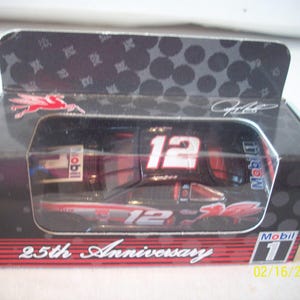 May include: A red, white, and black die-cast car with the number 12 on the side. The car is in a clear plastic case with a black background. The case has a red and white label that says "25th Anniversary" and "Mobil 1".