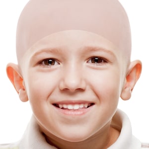 May include: A young boy with a shaved head smiles at the camera. He is wearing a white and brown striped polo shirt.