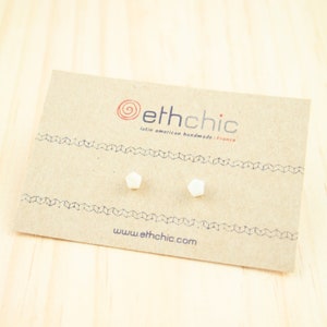 May include: A pair of white hexagonal stud earrings on a brown card with the text "ethchic latin american handmade - France www.ethchic.com"